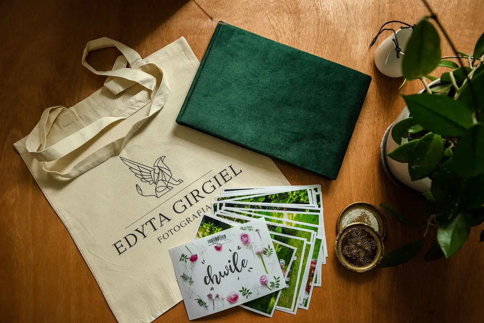 Elegancki zestaw fotograficzny Edyty Girgiel z albumem w zielonej okładce, ekologiczną torbą i selekcją zdjęć, prezentujący profesjonalizm i dbałość o każdy detal.